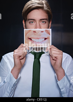 Man holding photo de dents sourire sur fond noir. La forme verticale, vue avant, jusqu'à la taille Banque D'Images