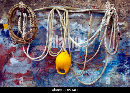 Corde et la bouée accrochée à un mur de chantier gallois, éclaboussé par diverses peintures de couleur. Banque D'Images