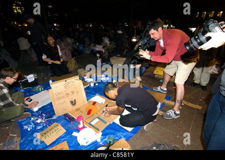 Occupy Wall Street manifestants assis sur le sol à peint des affiches pour la nuit prochaine journée de mars tandis que news media film eux Banque D'Images