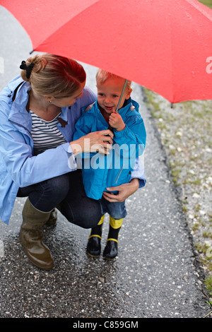 La mère et le fils avec parapluie sur route Banque D'Images