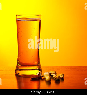 Verre de bière froide en verre et les écrous isolé sur fond chaud jaune, festival de la bière, maison de vacances Banque D'Images