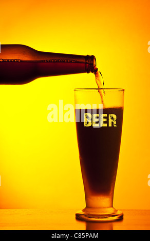 Waiter pouring beer foncé, verre d'une boisson froide isolé sur fond chaud jaune, festival de la bière, maison de vacances Banque D'Images