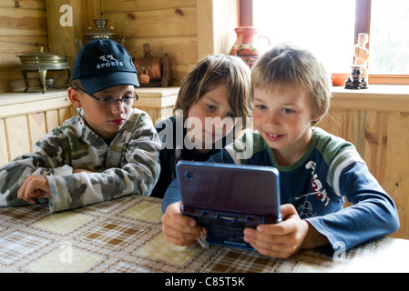 Pologne, Parc National de la rivière Biebrza, la vallée de mammouth (Mamucia Dolina), trois jeunes garçons profiter de jeux console Nintendo DS Banque D'Images