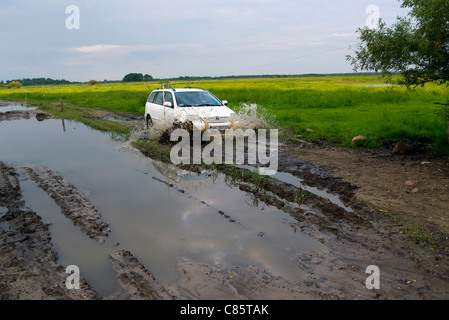 Pologne, Parc National de la rivière Biebrza, pêcheur ayant du mal à revenir par route boueuse de la rive de la rivière. Banque D'Images