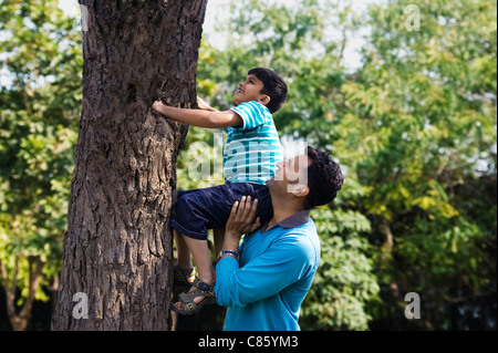 Père aide son fils grimper à un arbre Banque D'Images