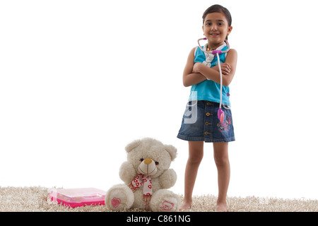 Jeune fille debout à côté de son ours en peluche Banque D'Images