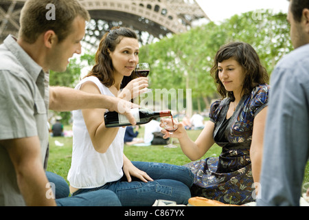 Friends enjoying wine at picnic près de Eiffel Tower, Paris, France Banque D'Images