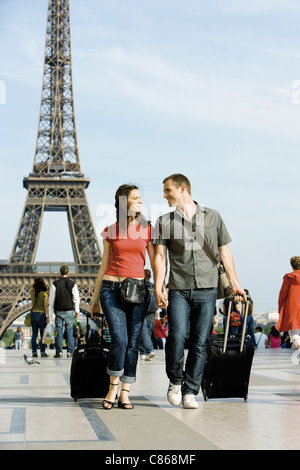 Couple en train de marcher avec assurance du matériel roulant près de Eiffel Tower, Paris, France Banque D'Images