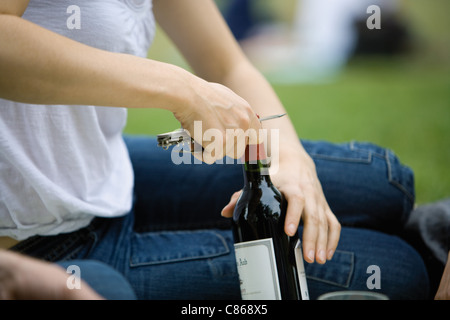 Femme déboucher une bouteille de vin à l'extérieur, cropped Banque D'Images