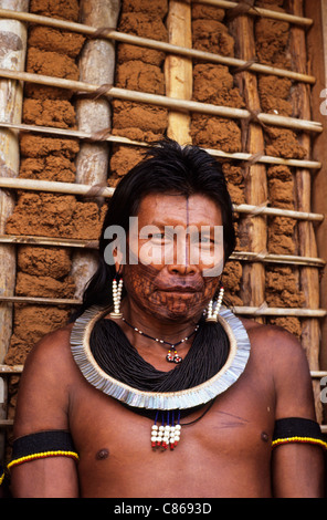 Un Ukre-Village, au Brésil. Portrait d'un homme Kryt, Kayapo avec la face noire de la peinture, colle et shell avec parure et enduits mur. Banque D'Images