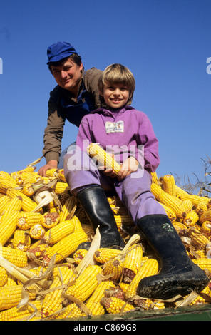 La Slovénie. Smiling farmer et sa fille sur une charge remorquée de maïs (maïs). Banque D'Images