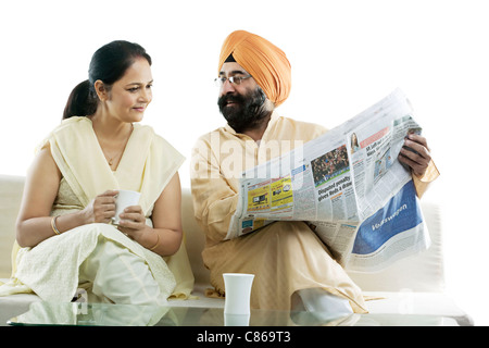 Homme Sikh montrant un article dans le journal à sa femme Banque D'Images