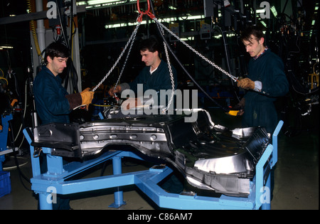 Bratislava, Slovaquie : Volkswagen usine ; trois travailleurs, en plaçant une plaque de sol en acier pressé sur une gigue. Banque D'Images