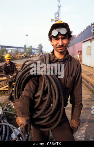 Gdansk, Pologne. Shipyard worker wearing hard hat et des lunettes de soudure d'un câble. Banque D'Images