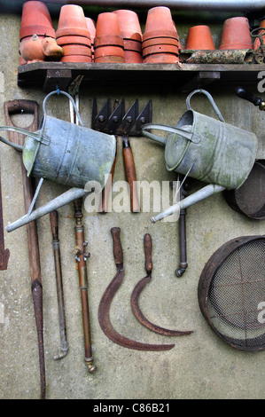 Outils de jardin suspendu à une paroi de l'habitacle et une étagère de pots de fleurs UK Banque D'Images