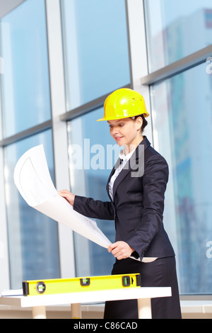 Une jeune femme architecte dans un plan d'un casque Banque D'Images