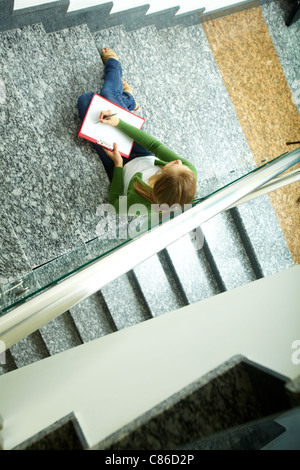 Au-dessus de l'angle pretty student sitting on stairs de College et la pensée d'idées Banque D'Images