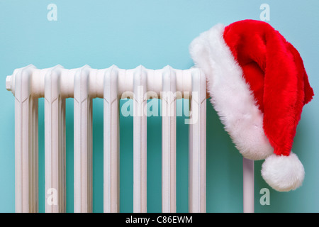 Photo d'un Père Noël rouge et blanc hat hanging sur un vieux radiateur en fonte traditionnelle. Banque D'Images