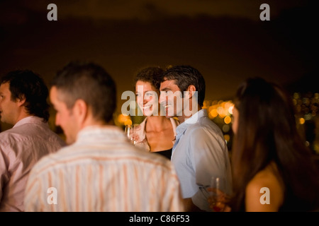 Les personnes ayant des vins sur la terrasse la nuit Banque D'Images