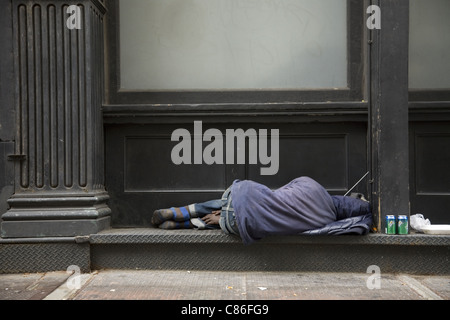 Sans-abri dort sur un rebord du bâtiment à Manhattan. Banque D'Images