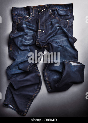 Photo de manière artistique en pierre bleu froissé mens jeans sur fond gris Banque D'Images