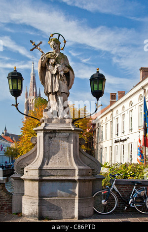 Statue de saint Jean Népomucène, Sint-Jan Nepomucenus, sur pont Wollestraat à Bruges. Tour de l'église de Notre Dame en arrière-plan. Banque D'Images