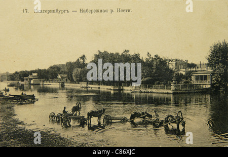 Les chevaux s'assourdient sur le point d'arrosage de la rivière Iset à Yekaterinburg, Empire russe. Photo vintage noir et blanc du photographe russe Veniamin Metenkov datée du début du XXe siècle, publiée dans la carte postale russe vintage publiée par Veniamin Metenkov lui-même à Yekaterinburg. Texte en russe: Yekaterinburg. Remblai de la rivière Iset. Avec la permission de la collection de cartes postales Azoor. Banque D'Images