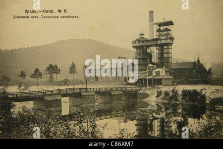 Le haut fourneau dans une usine non spécifiée des Monts de l'Oural, Empire russe. Photo vintage noir et blanc du photographe russe Veniamin Metenkov datée du début du XXe siècle, publiée dans la carte postale russe vintage publiée par Veniamin Metenkov lui-même à Yekaterinburg. Texte en russe: L'Oural. Four à explosion. Plate-forme d'usine. Avec la permission de la collection de cartes postales Azoor. Banque D'Images