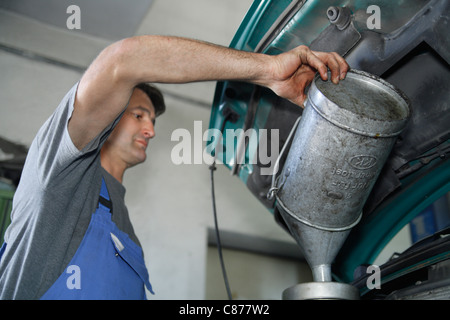 L'Allemagne, l'Ebenhausen, technicien en mécatronique en versant de l'huile voiture au garage voiture Banque D'Images