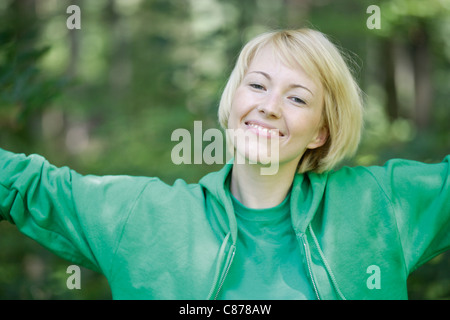 Allemagne, Bavière, Schaeftlarn, Close up of young woman in forest with arms up, portrait, smiling Banque D'Images