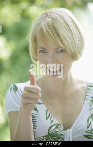 Allemagne, Bavière, Schaeftlarn, Close up of young woman showing her Thumbs up, smiling, portrait Banque D'Images