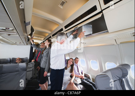 Germany, Bavaria, Munich, les passagers de la dépose des bagages à main à partir de la tablette dans airplane cabin Banque D'Images