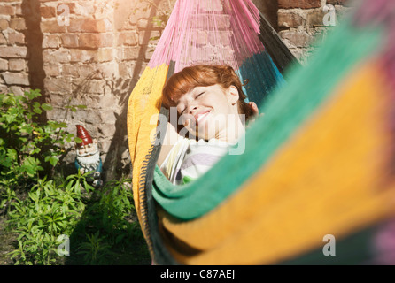 Allemagne, Berlin, young woman in hammock, smiling Banque D'Images