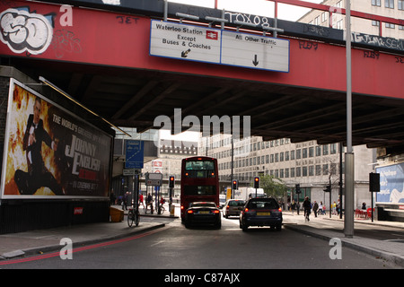 Un bus et des voitures en attente sous un pont pour les feux de circulation pour changer du rouge au vert Banque D'Images