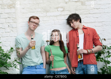 Allemagne, Berlin, young men and woman holding beer bottles, smiling Banque D'Images