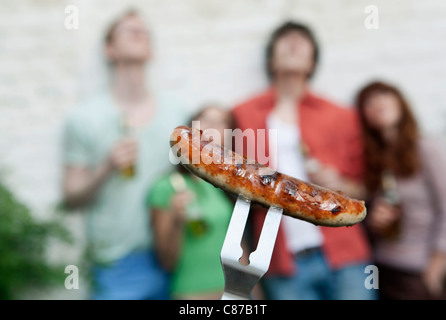 Allemagne, Berlin, Close up de saucisses grillées sur fourche avec des amis en arrière-plan Banque D'Images