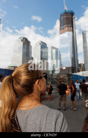 Une femme regarde la Freedom Tower (One World Trade Center), tout en se tenant par l'entrée du Mémorial National du 11 septembre à New York. Banque D'Images