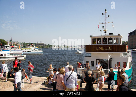 Les touristes sur le quai, la location de bateaux à passagers, avec Grona Lund amusement park en arrière-plan, le port de Stockholm, Suède, Banque D'Images