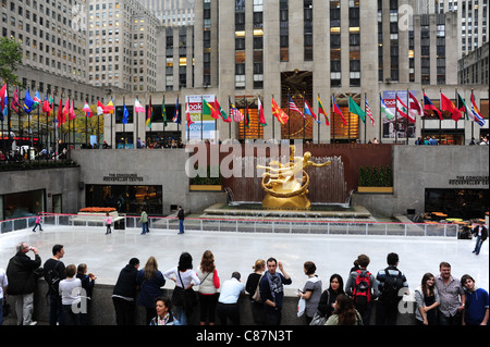 Regarder les gens, les patineurs d'or à Prométhée sculpture, drapeaux, '30 Rock', patinoire, Rockefeller Center, New York, USA Banque D'Images