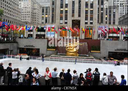 Regarder les gens patineurs sur glace, vers l'or de la sculpture, drapeaux, Prométhée '30 Rock. Patinoire du Rockefeller Center, New York, USA Banque D'Images