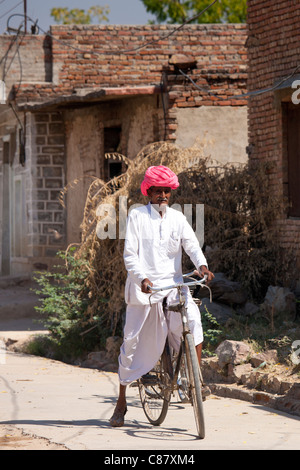 L'homme indien en costume traditionnel riding bicycle in Jawali village de Rajasthan, Inde du Nord Banque D'Images