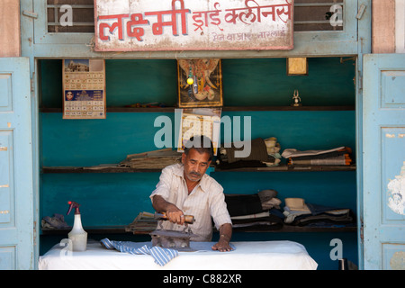 L'homme indien pressage des vêtements dans son atelier à Narlai village de Rajasthan, Inde du Nord Banque D'Images