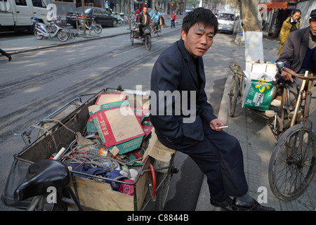 Le recyclage dans les rues de Hangzhou, Chine. Les travailleurs migrants itinérants prend une pause cigarette à partir de la collecte des déchets pour recyclage Banque D'Images