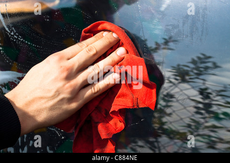 La main de l'homme avec chiffon rouge lave-vitre de voiture. Banque D'Images