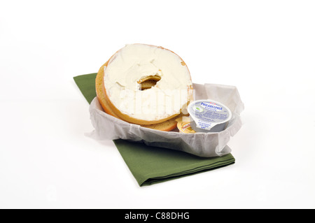 Bagel nature avec le fromage à la crème Philadelphia contenants dans une corbeille à papier avec serviette verte sur fond blanc, cut out. Banque D'Images