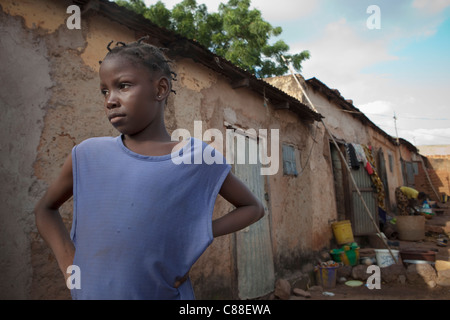 Une jeune fille se tient devant sa maison familiale à Bamako, Mali, Afrique de l'Ouest. Banque D'Images