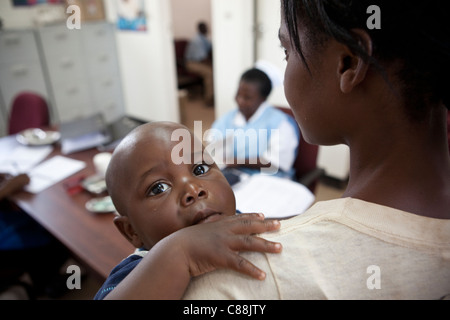 Une mère amène son jeune enfant à une clinique DE LUTTE CONTRE LE SIDA soutenu par le Secours catholique à Lusaka, Zambie. Banque D'Images