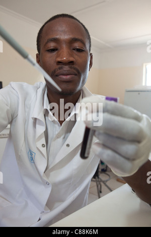 Un des techniciens de laboratoire des échantillons de sang d'essai des patients atteints du VIH dans un hôpital de Luanshya, Zambie. Banque D'Images