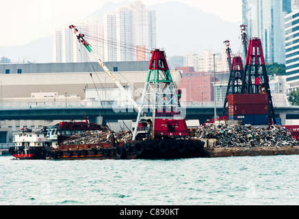 Le traitement de la ferraille sur la jetée avec chaland Barge avec grande grue à Victoria Harbour Kowloon Hong Kong Chine Asie Banque D'Images