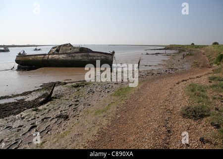River Ore / Alde, banque / mur à Orford Suffolk, UK montrant abandonné bateau en bois en arrière-plan Banque D'Images